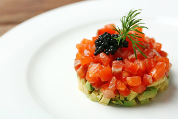 Delicious salmon tartare with black caviar on white plate