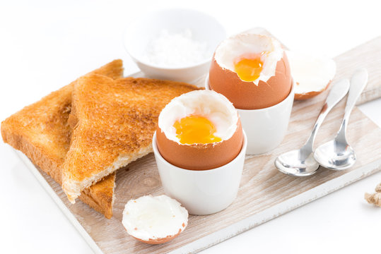 boiled eggs and crispy toasts on a wooden board, closeup