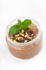 chocolate dessert with pistachios in a glass jar, top view