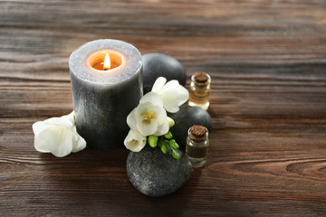 Spa composition with candle, pebbles and aroma oil on wooden background