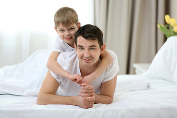 Portrait of son and father lying in bed at home