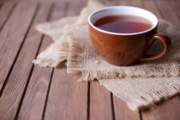 Cup of tea on wooden table with sackcloth closeup