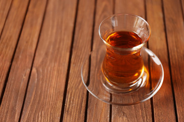 Glass of black tea on wooden background