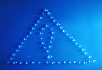 Naklejka na ściany i meble Triangle and exclamation mark made of water drops on blue background