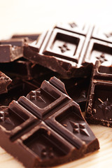 Dark chocolate broken into pieces on a wooden table