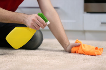 Male hands cleaning carpet indoors