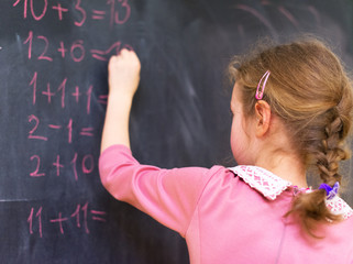 Schoolgirl solving simple equations at school.