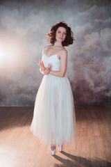 Fototapeta na wymiar Ballerina in a white bathing suit and of long skirt with a beautiful body standing on pointe shoes, lifestyle, hobbies, dancing, choice