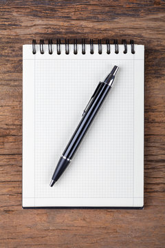 Blank note pad with pen on wood background