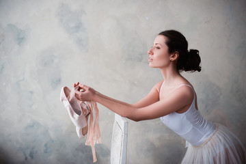 Portrait of a beautiful young ballerina holding hands pointe shoes for dance, lifestyle, hobbies, close up