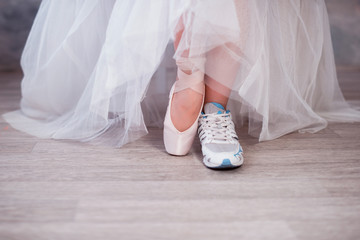 Legs of a ballerina, one foot shod in sneakers other in pointe shoes, lifestyle, hobbies, dancing,...