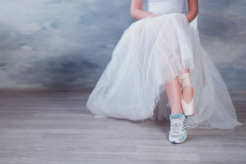 Obraz premium Legs of a ballerina, one foot shod in sneakers other in pointe shoes, lifestyle, hobbies, dancing, choice