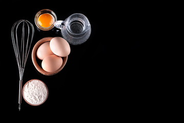 whisk and ingredients on a black background