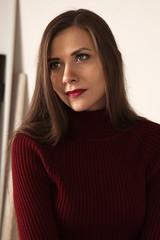 portrait of a beautiful young dark haired woman in a red turtle neck sweater red lips looking sideways photoshoot