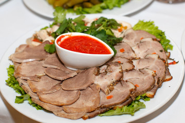 Cutting the meat and tongue and sauce on a white plate Close-up