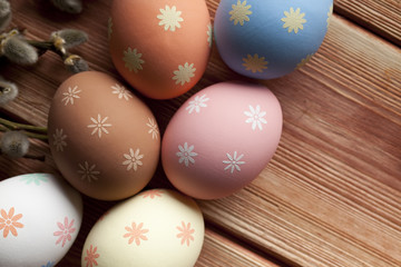 Colorful Easter eggs and pussy willow on wooden planks