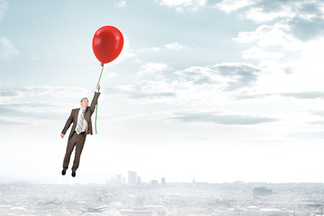 Businessman holding balloon and flying