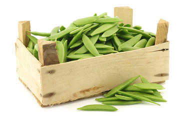 sugar snaps in a wooden crate on a white background