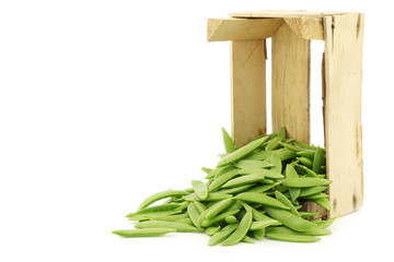 sugar snaps in a wooden crate on a white background