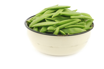 sugar snaps in an enamel bowl on a white background