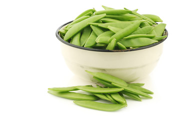 sugar snaps in an enamel bowl on a white background