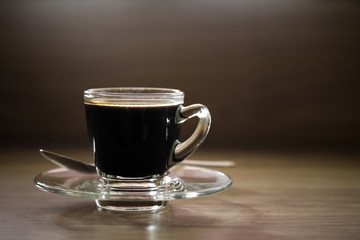 Black coffee cup and spoon on wood