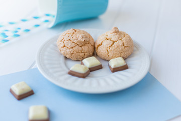 still life with coconut and chocolate cookies on a white wooden background. Blue cup with straws
