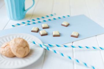 cookies on a white plate and pieces of chocolate on white blue background