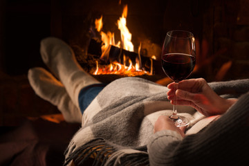 Femme se reposant avec le verre de vin près de la cheminée