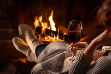 Photo sur Plexiglas Vin Femme se reposant avec un verre de vin près de la cheminée