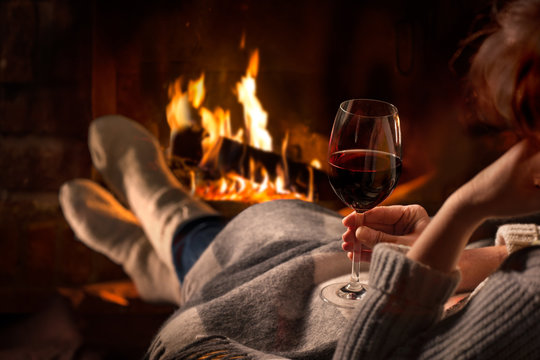 Woman resting with wine glass near fireplace