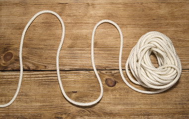 Hank of white rope on the wooden background