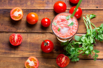 Gass of tomato smoothie, fresh tomatoes and cilantro on a dark wooden background . Vegetarian or healthy eating concept