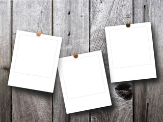 Close-up of three asymmetrical square blank photo frames with pins on monochrome wooden boards...