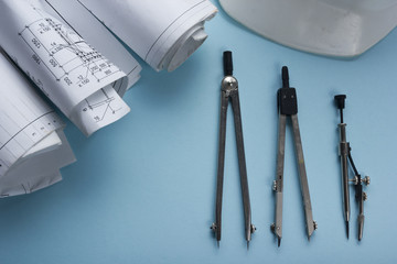 Architect worplace top view. Architectural project, blueprints, blueprint rolls and  divider compass on desk table. Construction background. Engineering tools. Copy space