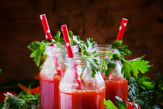 Spicy tomato juice in small bottles with straws, cherry tomatoes