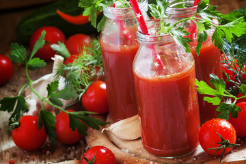 Spicy tomato juice in small bottles with straws, cherry tomatoes