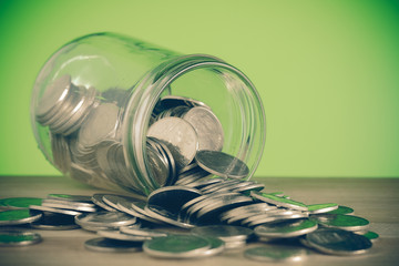 Coins spilling out of a glass bottle with filter effect retro vi