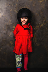 small girl in a red dress and helmet with ball in studio