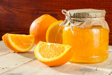 Банк апельсинового джема и несколько долек апельсина