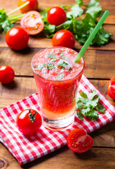 Gass of tomato smoothie, fresh tomatoes and cilantro on a dark wooden background . Vegetarian or healthy eating concept