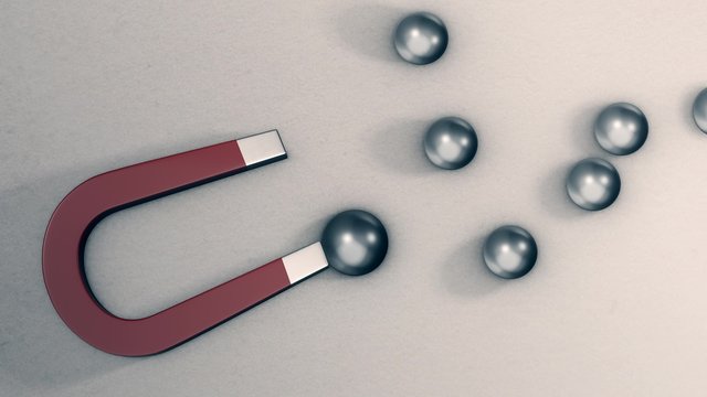 a magnet with some steel balls, one of them exceeds all the others and is pulled by the magnet, concept of competition and leadership (3d render)