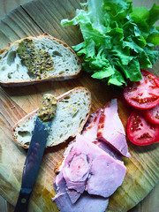 Cutting board with rye bread, ham slices, tomatoes and lettuce