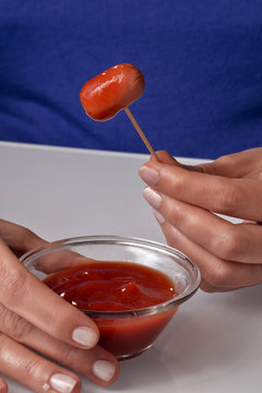 Comiendo mini salchichas con salsa ketchup, palillo con mini salchichas.