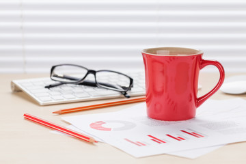 Office desk workplace with coffee and charts