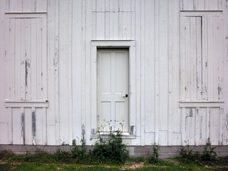 Centered door on white weathered wooden wall - landscape color photo