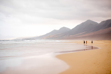 Cofete beach with people walking at the cloudy and foggy weather on Fuerteventura island in Spain