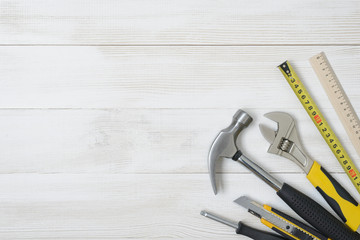 Top view of construction instruments and tools on wooden DIY workbench. with open space. Tape measure, wrench, hammer, cutter.