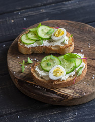 Healthy delicious breakfast or snack - open sandwich with goat's cheese and cucumber and boiled quail eggs