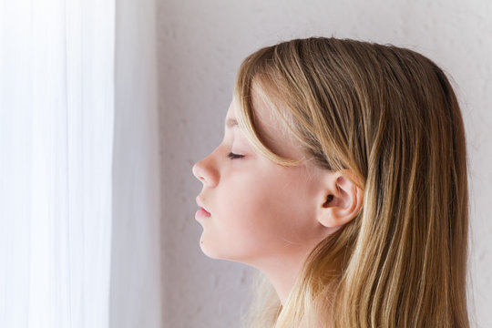 Caucasian girl with closed eyes near a window